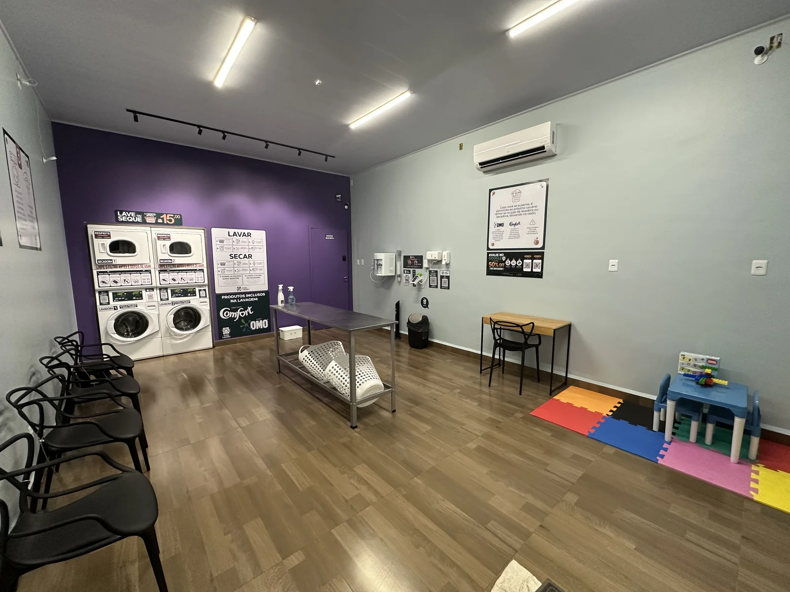 Visão ampla do interior da Estilo Laundry, com máquinas de lavar e secadoras
